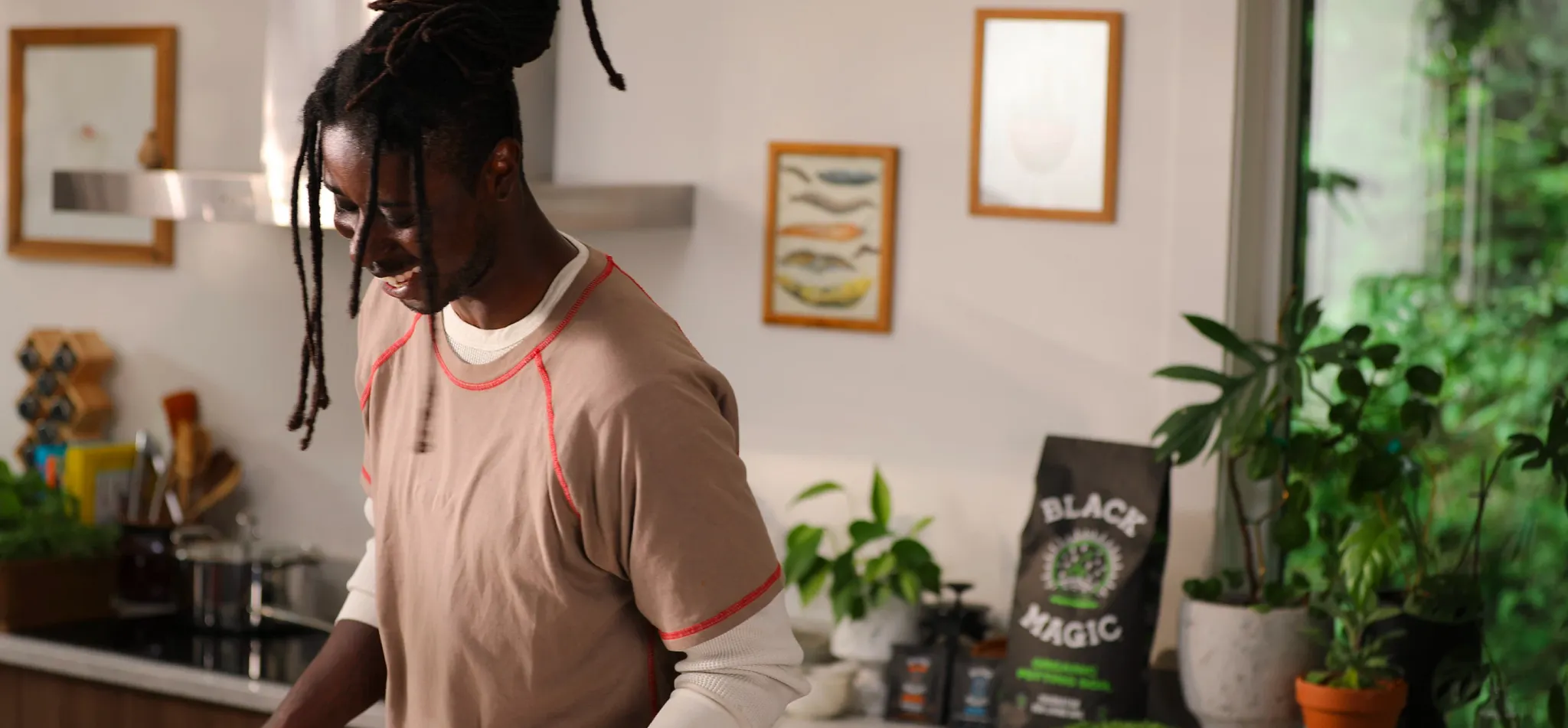 Person in a kitchen laughing with potted plants in the background.