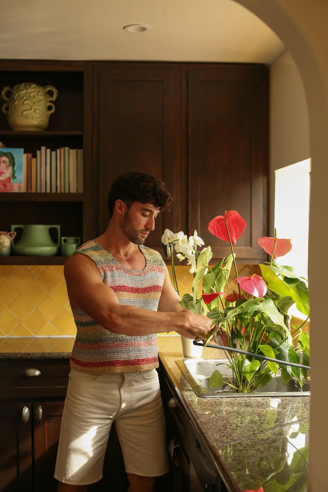 Brock and Chris in their kitchen watering a potted plant