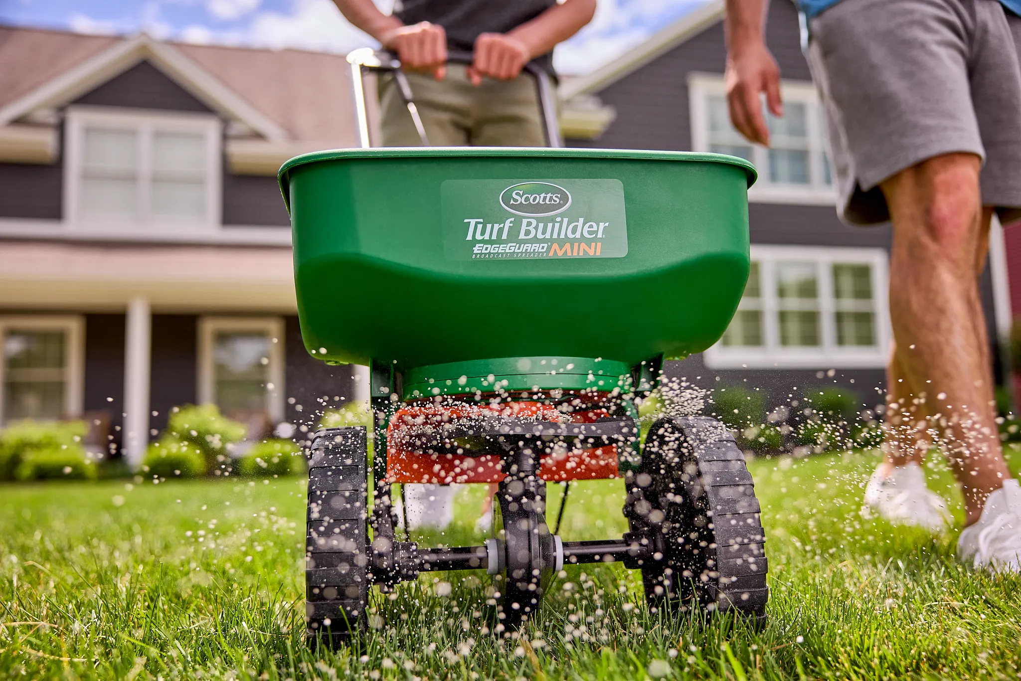 Scotts broadcast spreader applying lawn fertilizer