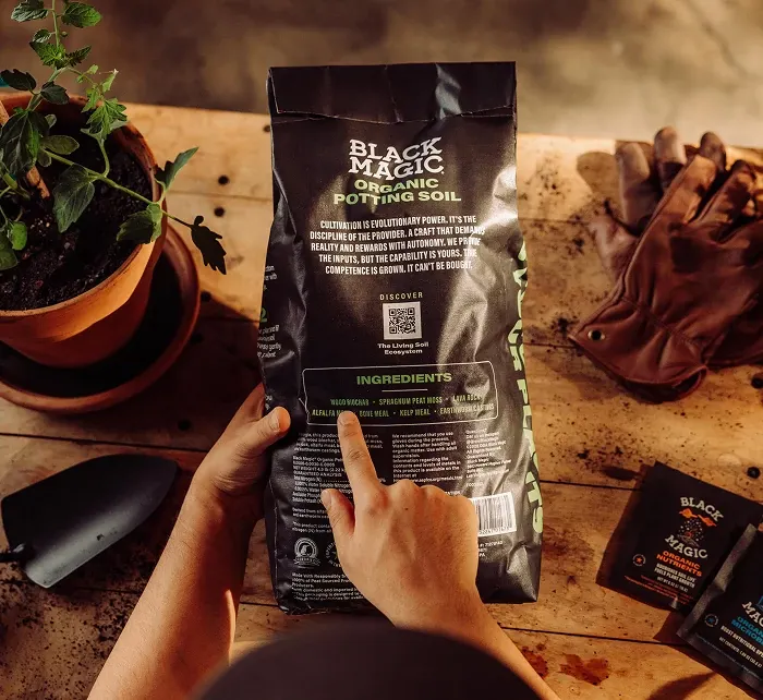 Person pointing to the back of the Black Magic Potting Soil bag