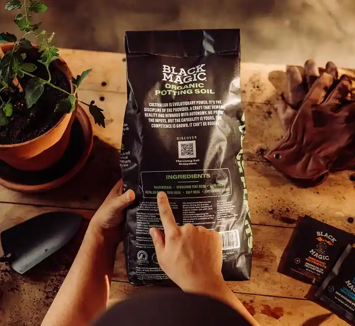 Person pointing to the back of the Black Magic Potting Soil bag