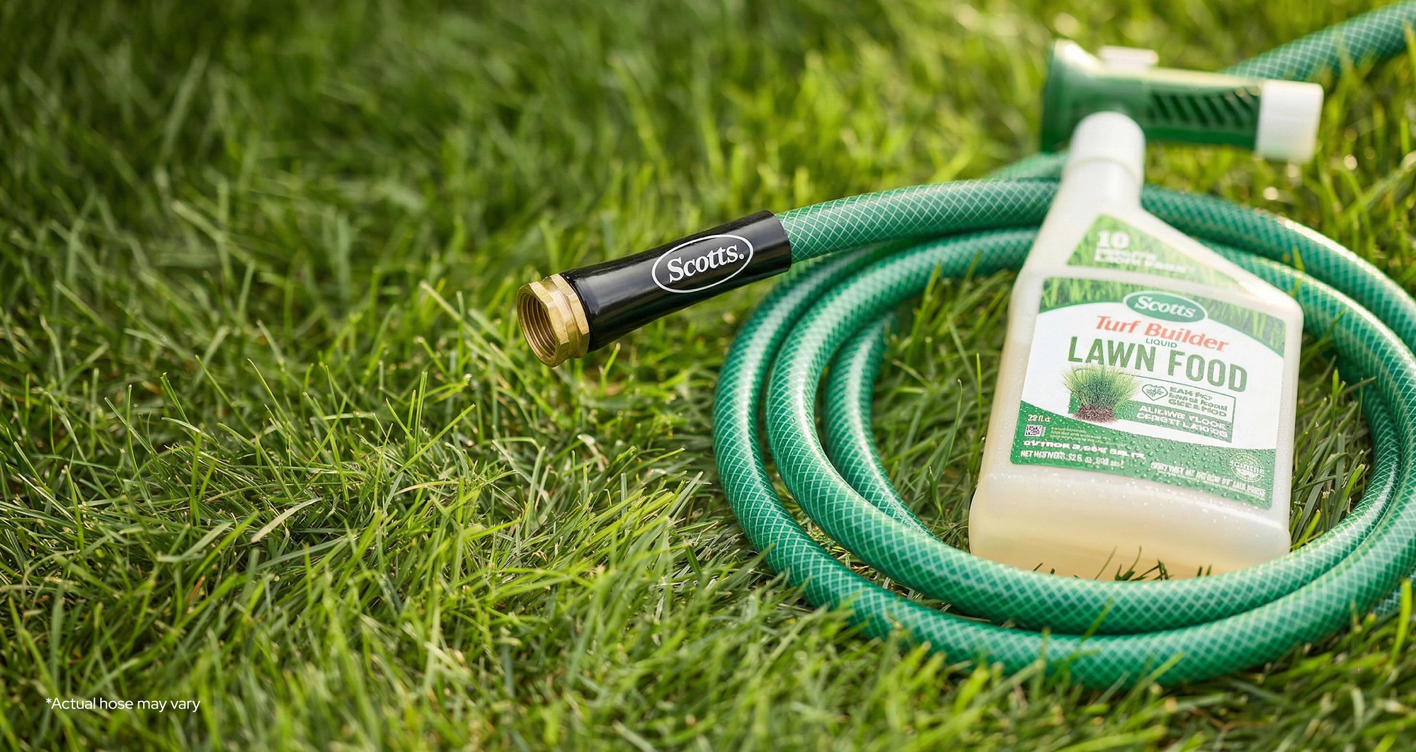 A bottle of Scotts Liquid Lawn Food sits on top of a green Scotts branded garden hose coiled up laying on a lush green lawn