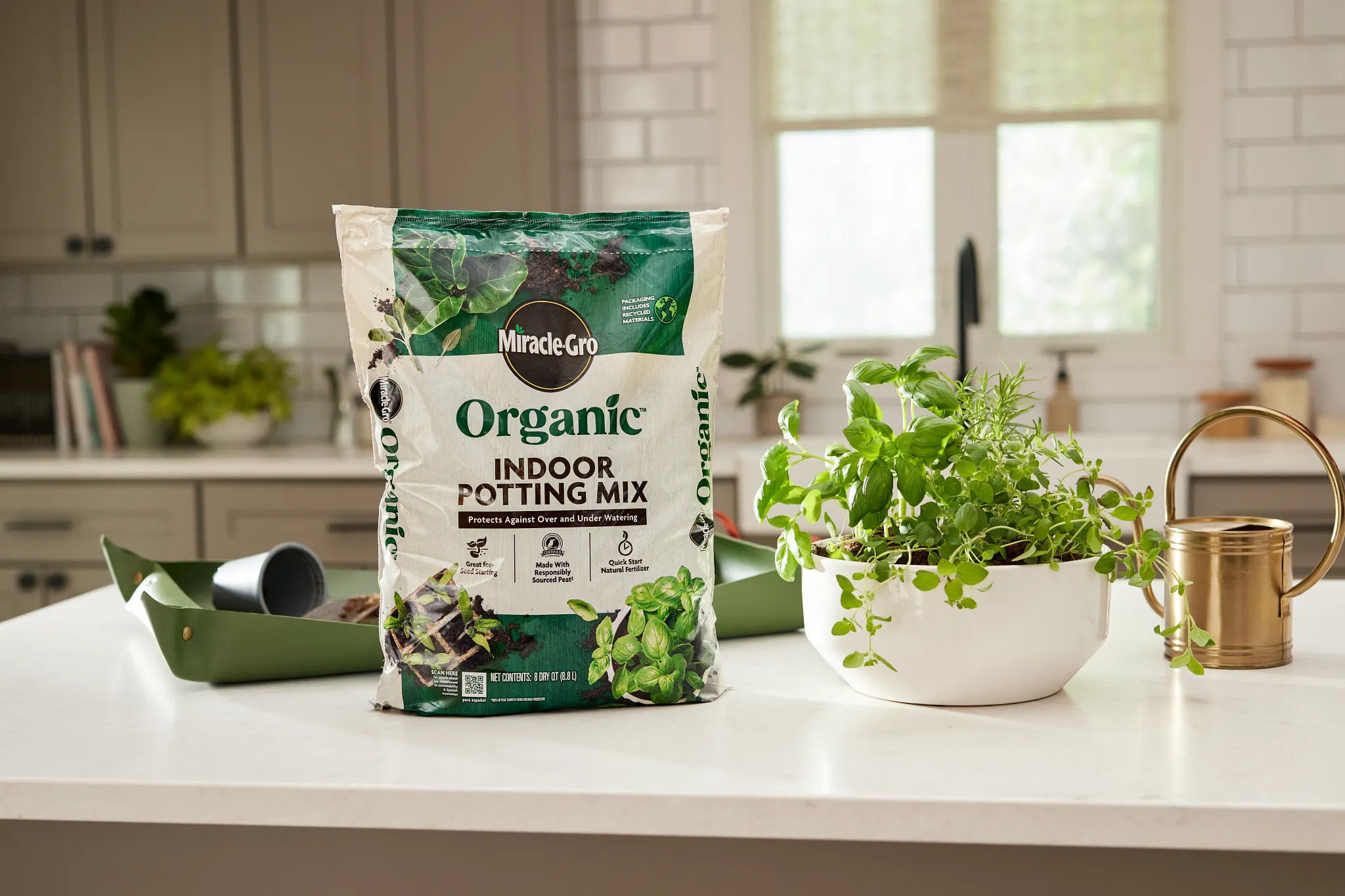 A bag of Miracle-Gro Organic Indoor Potting Mix sitting on a kitchen counter next to a potted container of herbs.