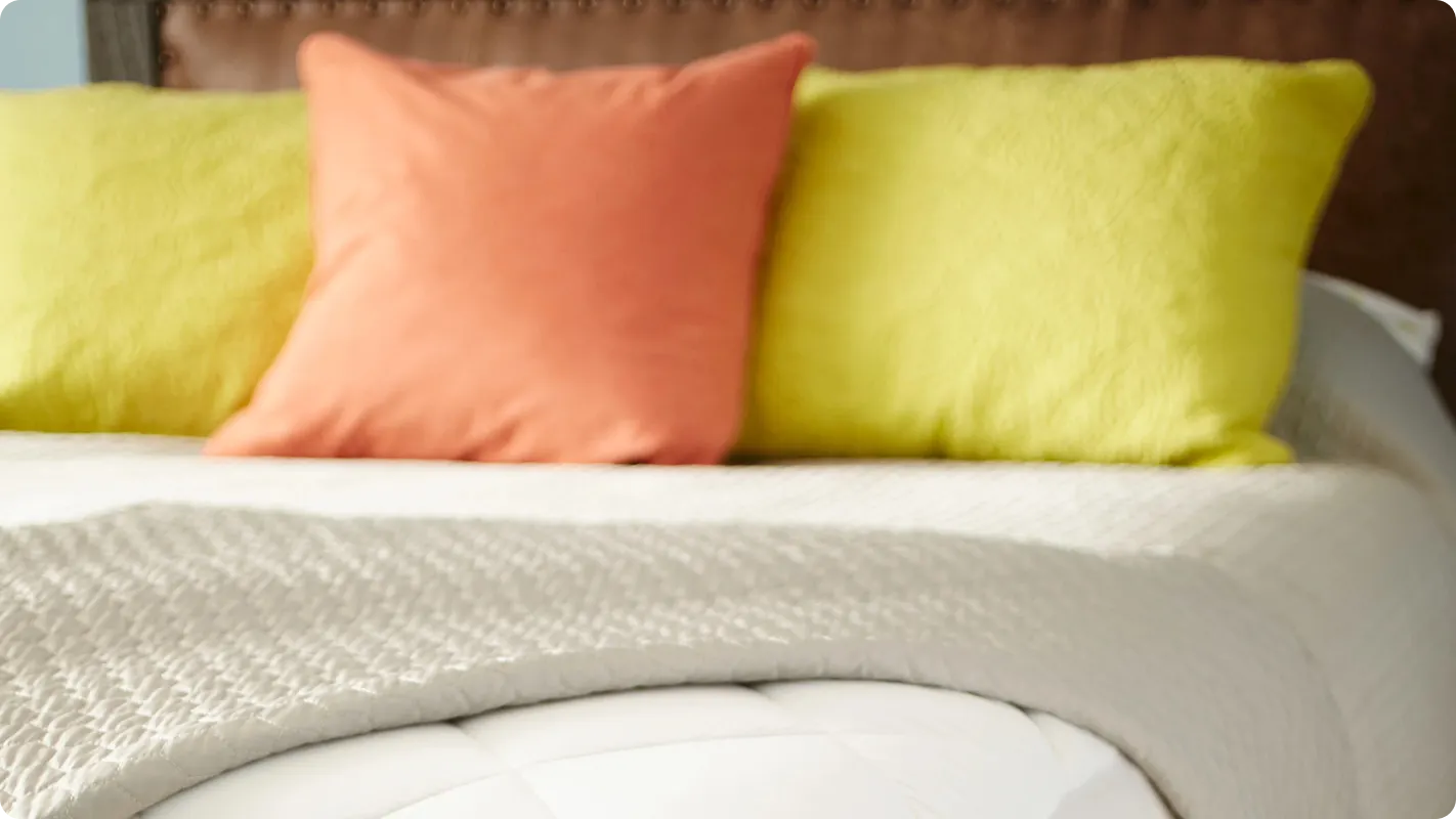 a bed with orange and yellow pillows