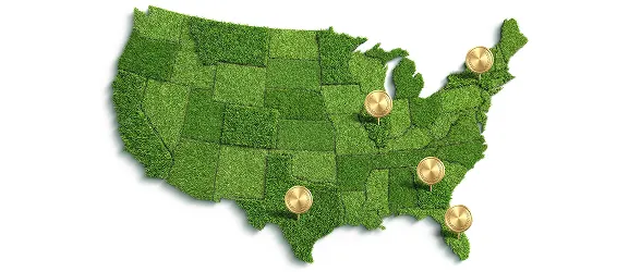 A map of the United States created from textured green grass sod, with five gold pushpins marking locations in Texas, Florida, Georgia, Illinois and New York States..