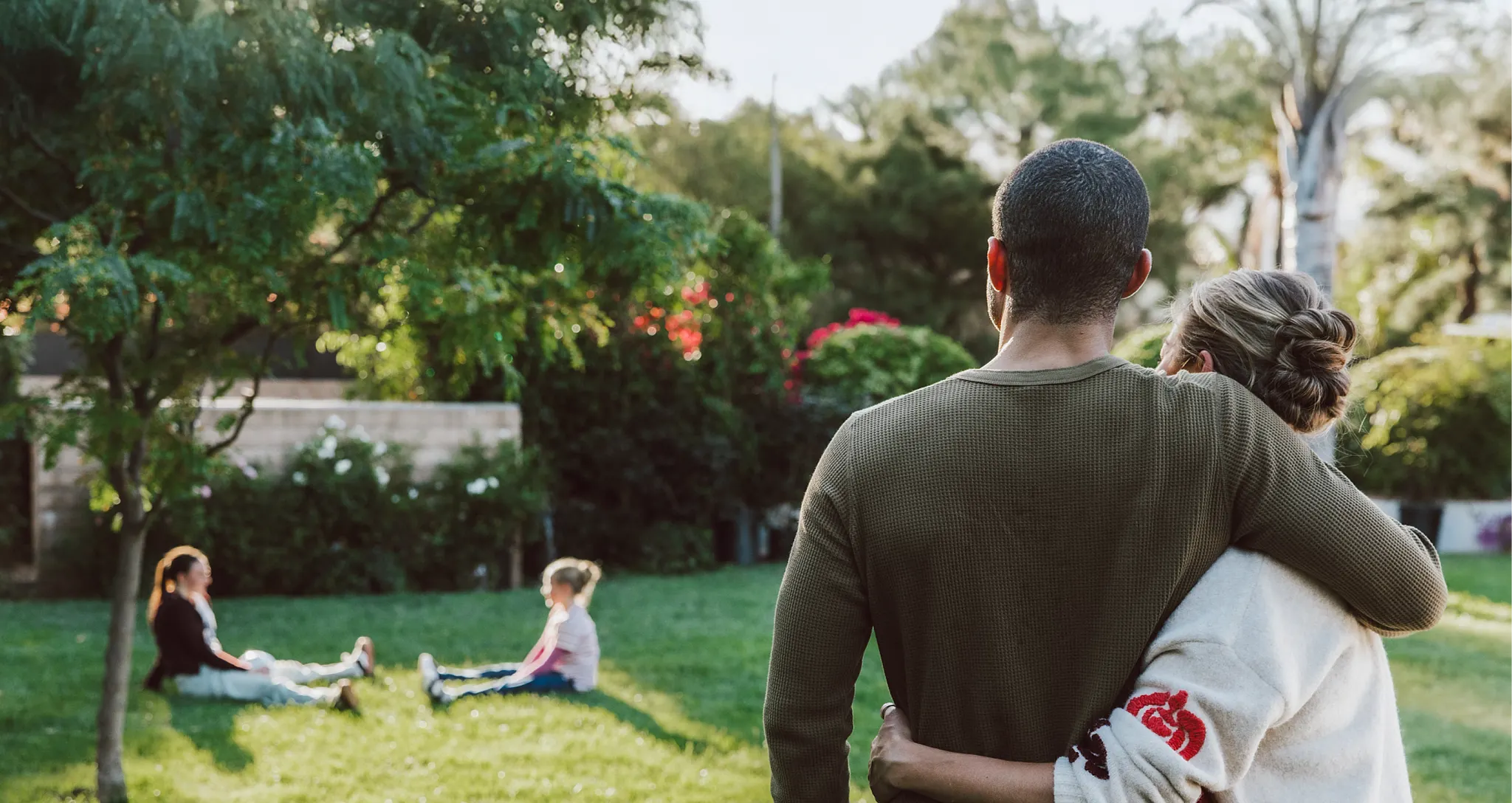 man and woman holding each other watching children