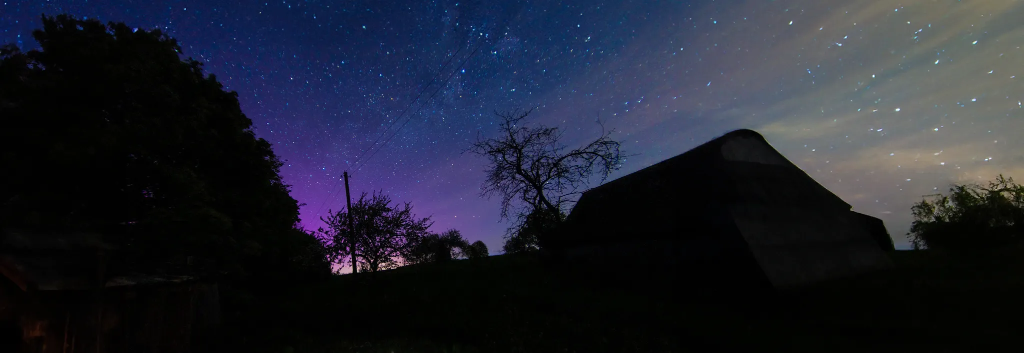 Text reflecting on how a backyard quietly reconnects a person to scale and the small distance between the infinite and the immediate, accompanied by a nighttime photo of a dark barn silhouette under a starry, purple-tinted night sky with a blue "H" callout icon.