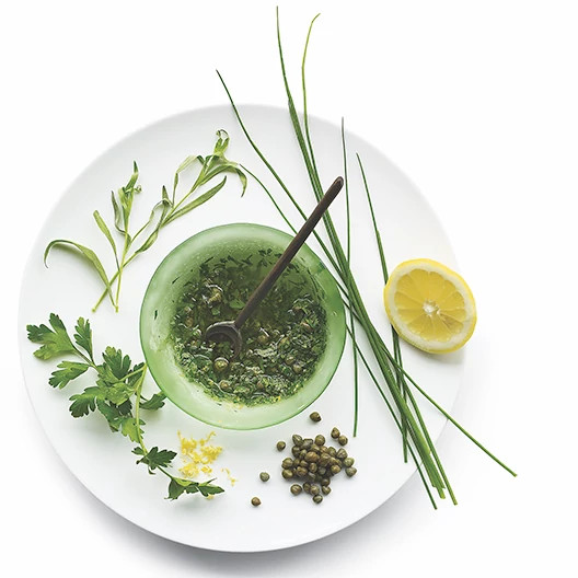salsa verde in a bowl surrounded by fresh herbs
