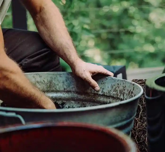 Hand mixing soil in a metal bin