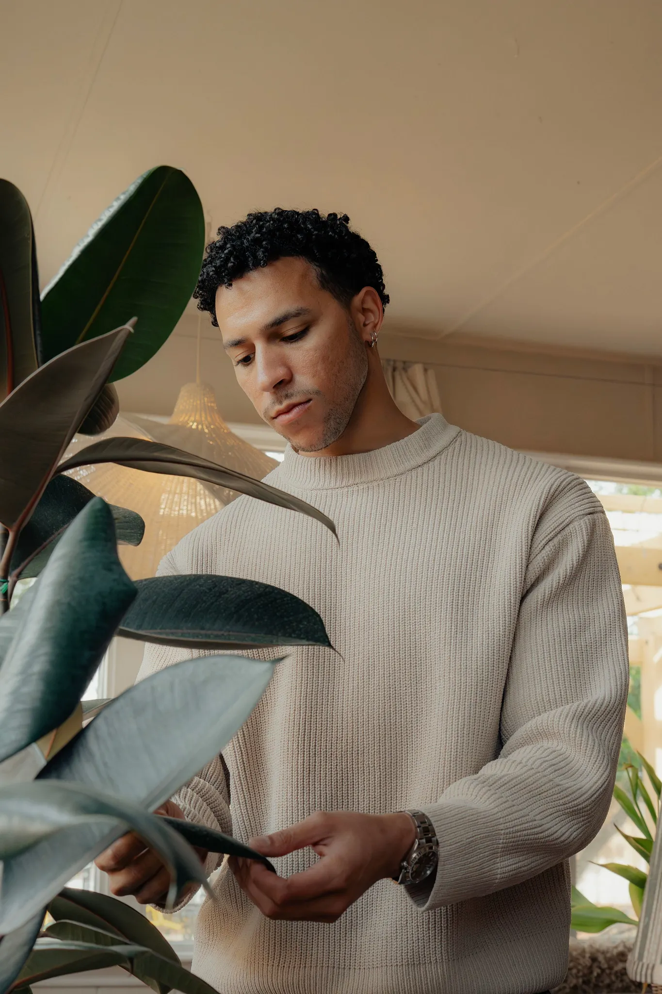 Terrence inspecting the leaves on one of his large potted tropical plants