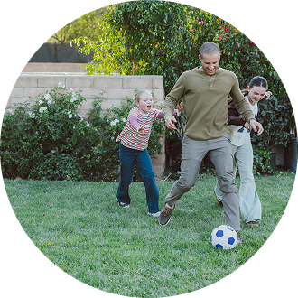 man and children playing soccer on lawn