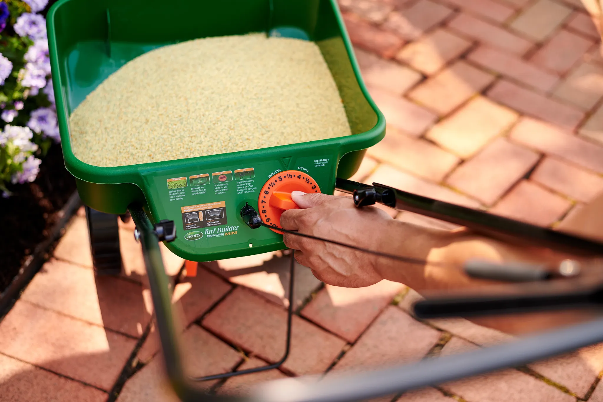 Setting the dial on a Scotts spreader before applying product.
