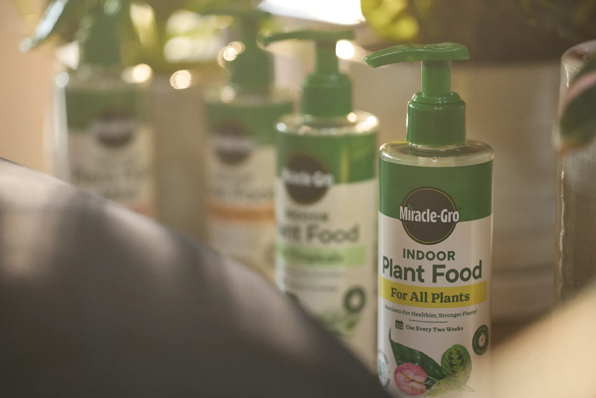 Miracle-Gro Plant Food squirt bottles sitting on a table in front of some potted plants
