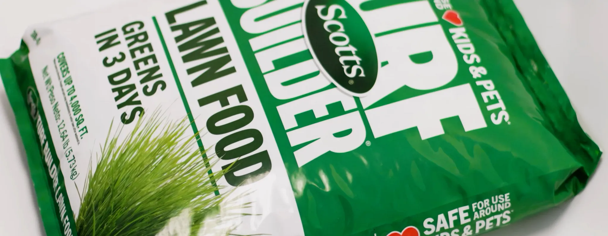 Close-up of a Scotts Turf Builder Lawn Food bag with a customer support text box overlay reading: Lawn Care with Confidence. Have questions beyond the bag? Our experts are here to help. Includes a Let's Chat button to connect with a lawn care expert.