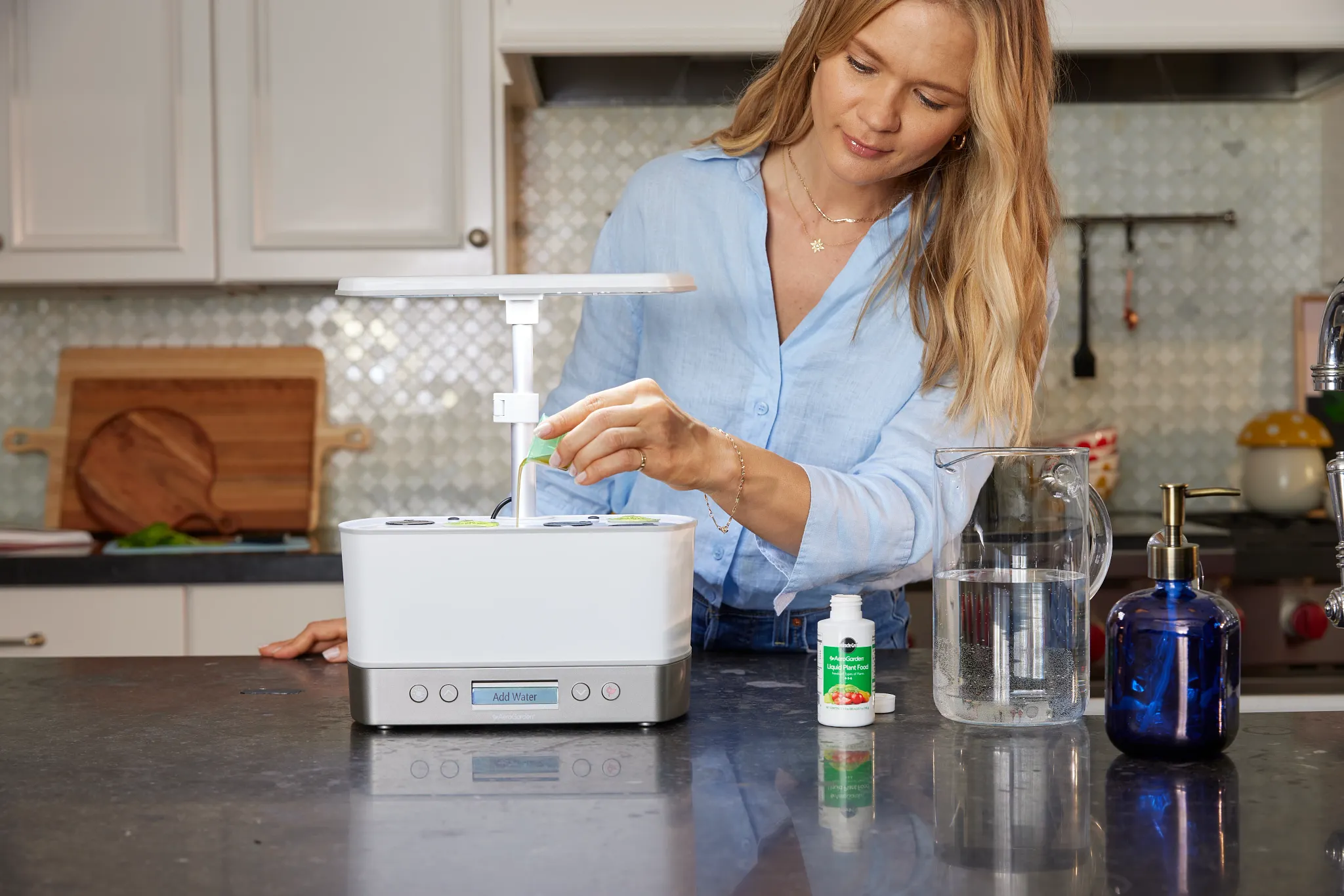 Woman in long-sleeve light blue shirt adds Plant Food to her AeroGarden unit