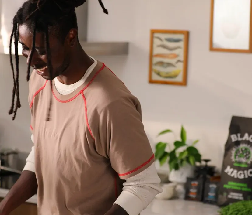 Person in a kitchen laughing with potted plants in the background.