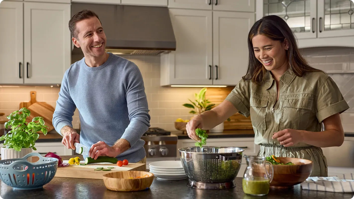 Man and woman making dinner together in the kitchen with their harvested garden vegetables