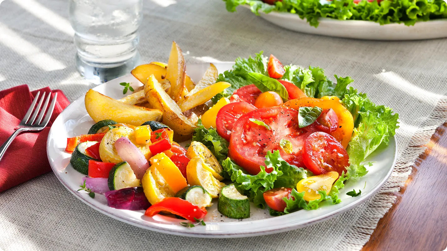 Plate of peppers, cucumbers , tomatoes, and other vegetables sitting on a table