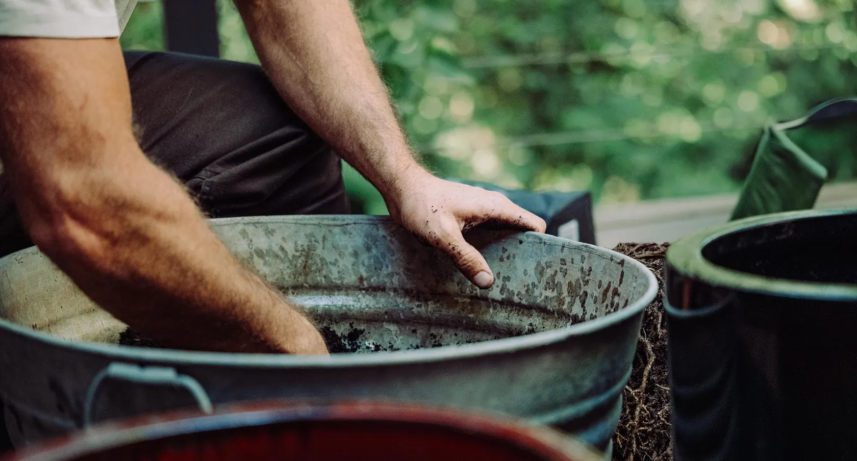 Hand mixing soil in a metal bin
