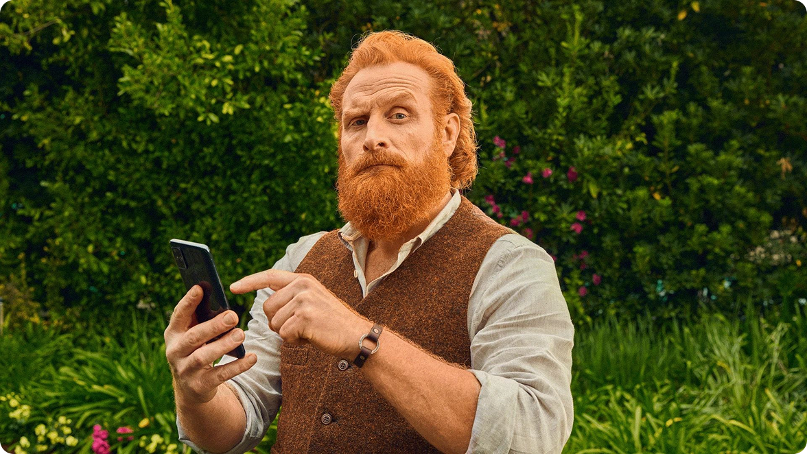 scotty with a phone standing in front of a hedge