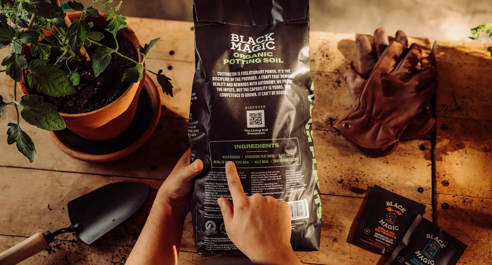 Person pointing to the back of the Black Magic Potting Soil bag