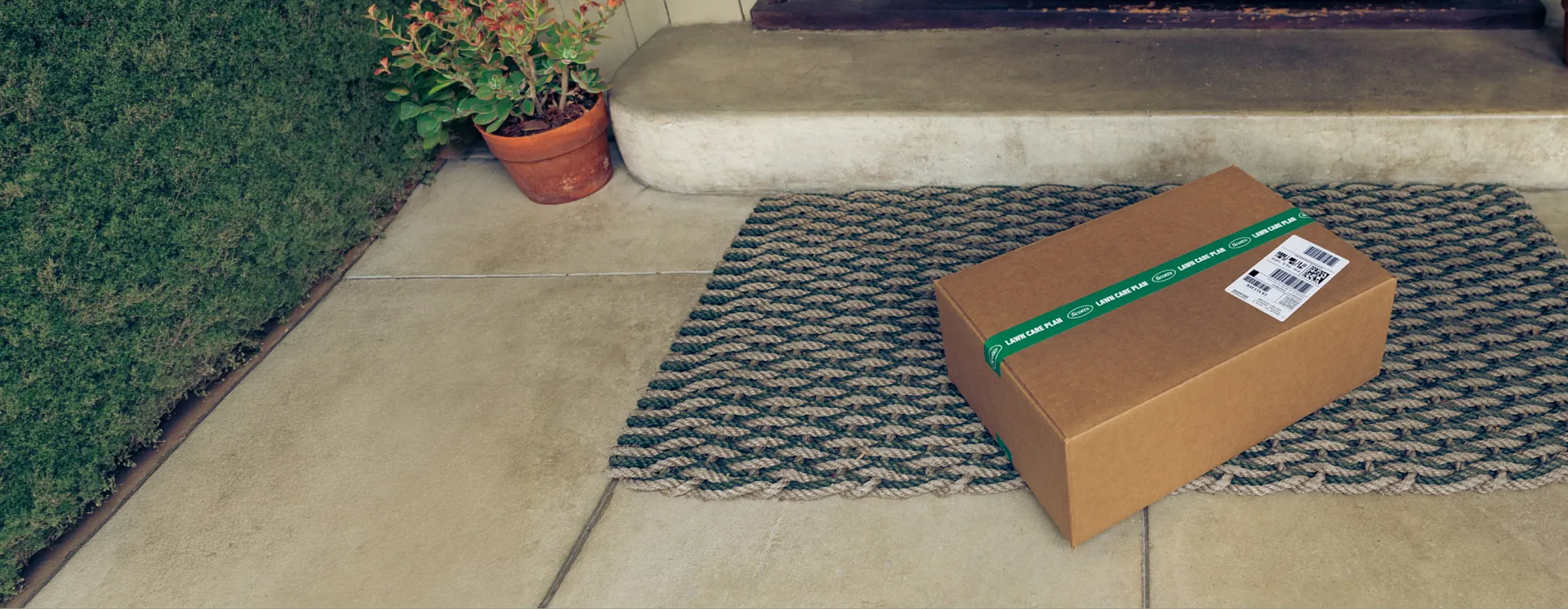 A Scotts lawn care plan delivery boc sitting on a front door step