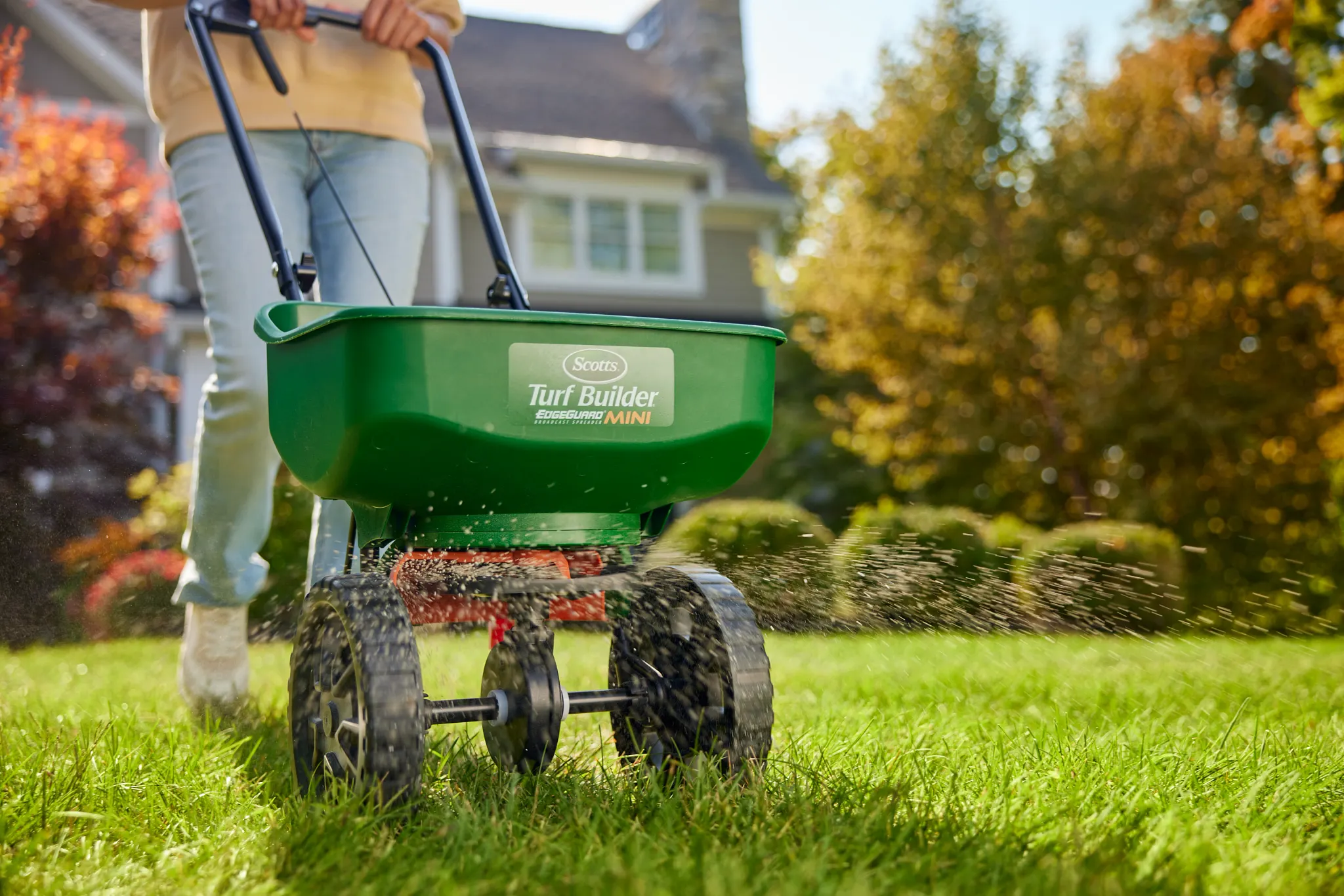 Scotts broadcast spreader applying product on fall lawn
