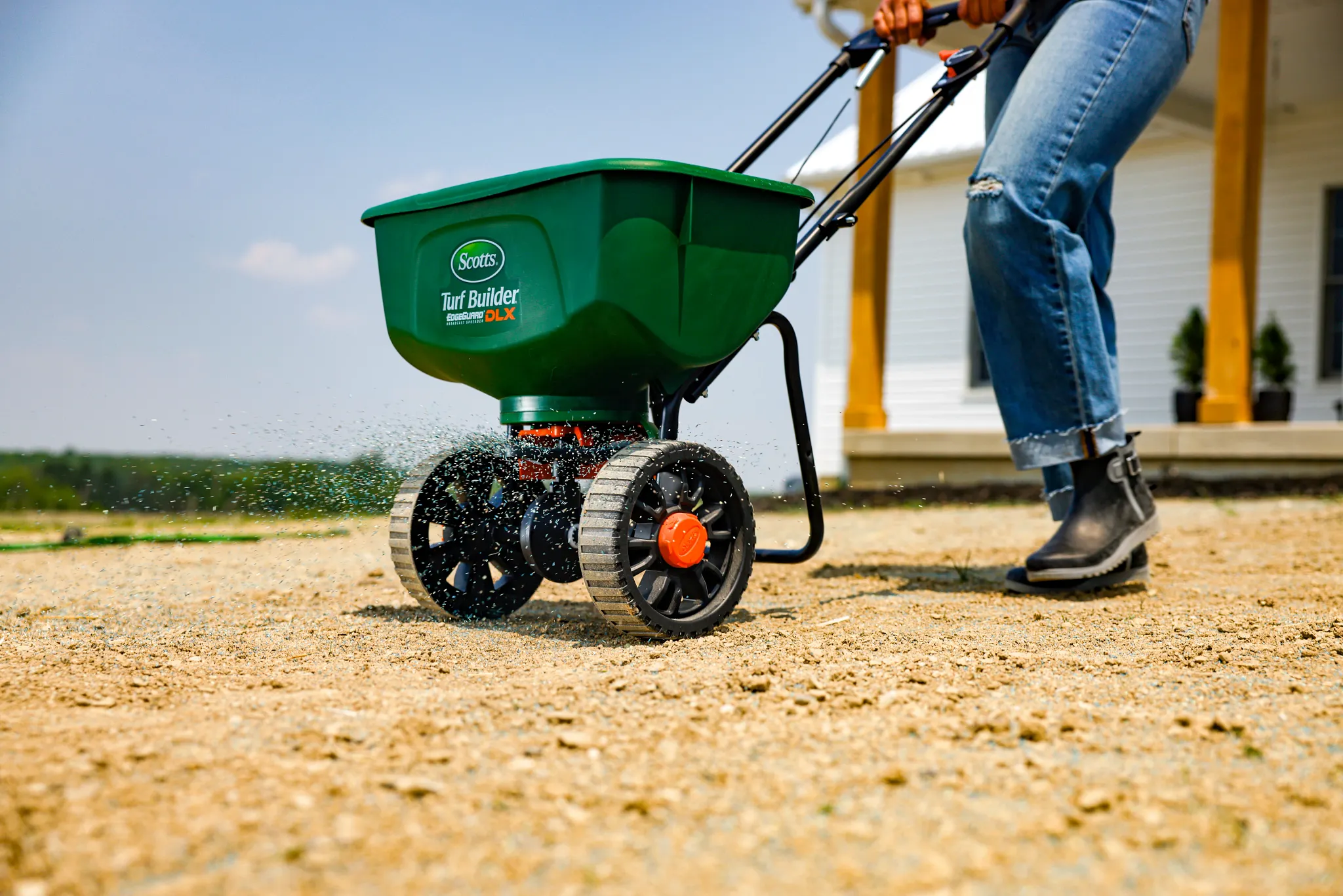 Planting a new lawn by applying grass seed to bare ground with a Scotts broadcast spreader.
