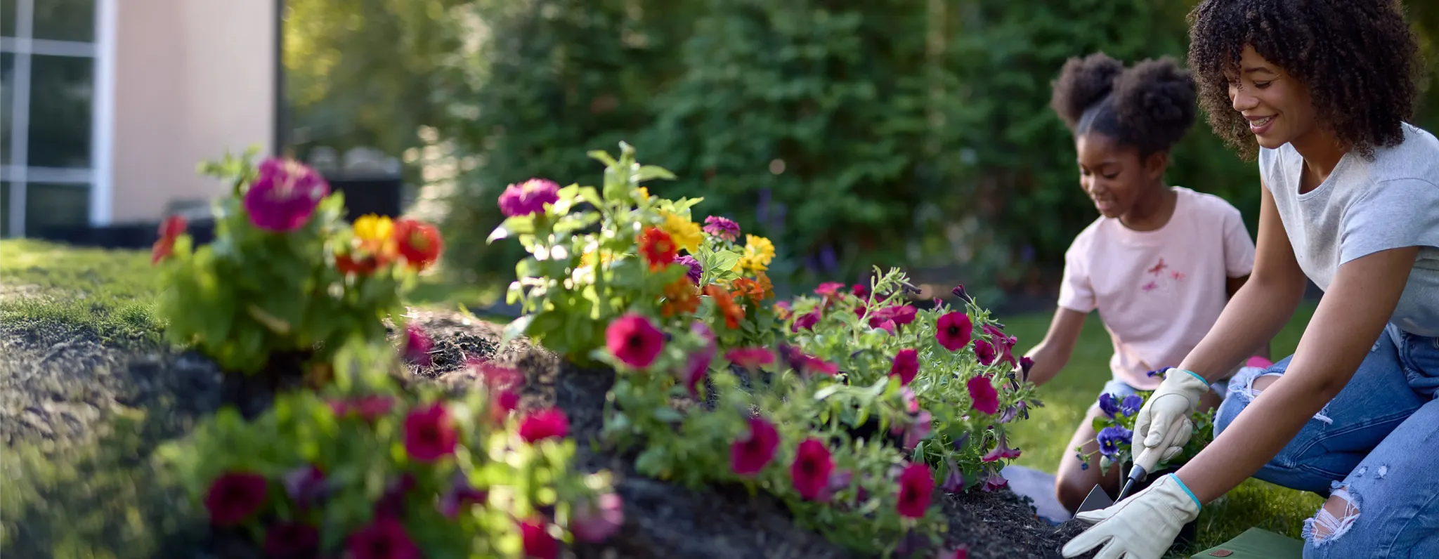 woman and child planting flowers in bed