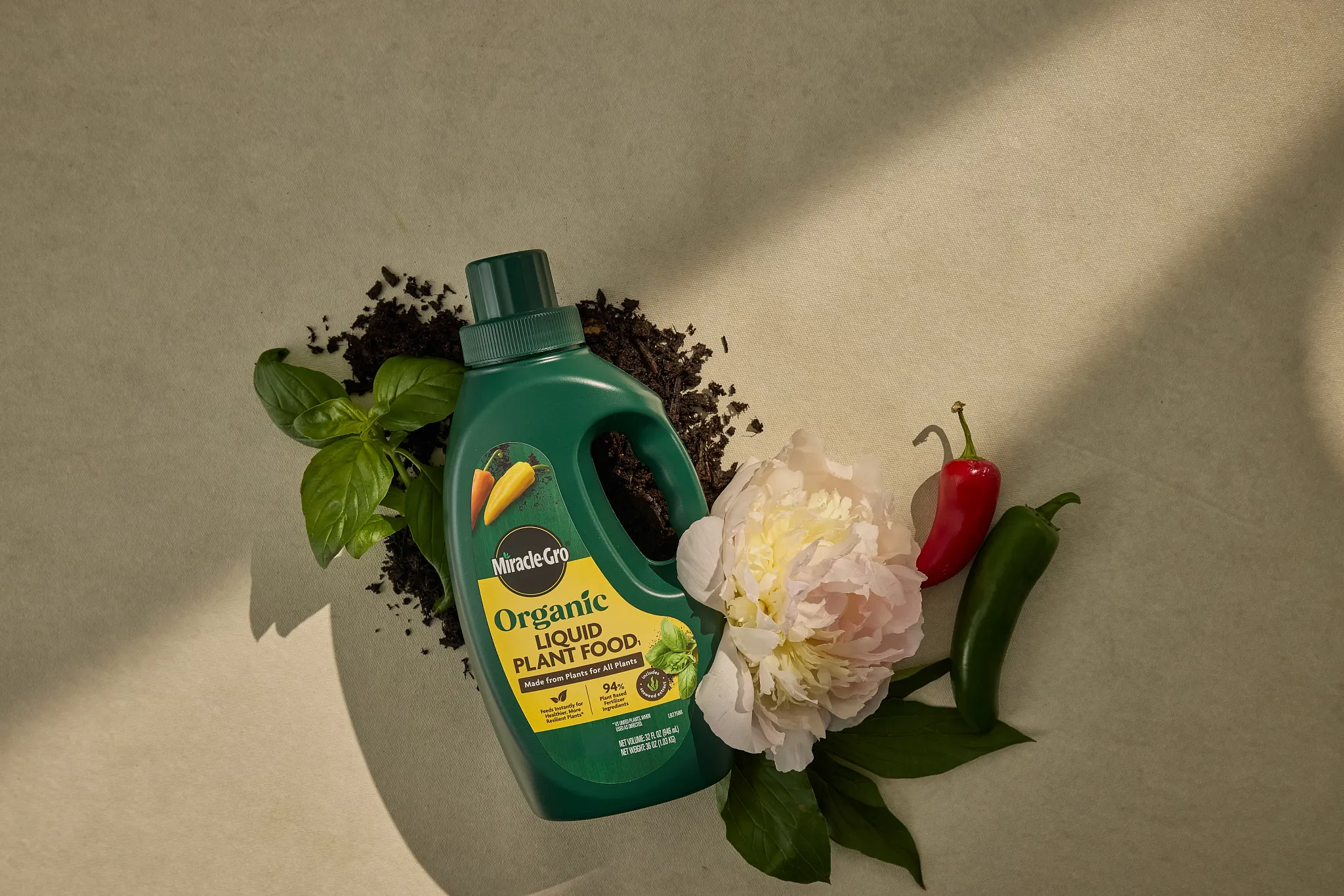 bottle of Miracle-Gro Organic Liquid Plant Food with soil, basil, peony, and hot peppers
