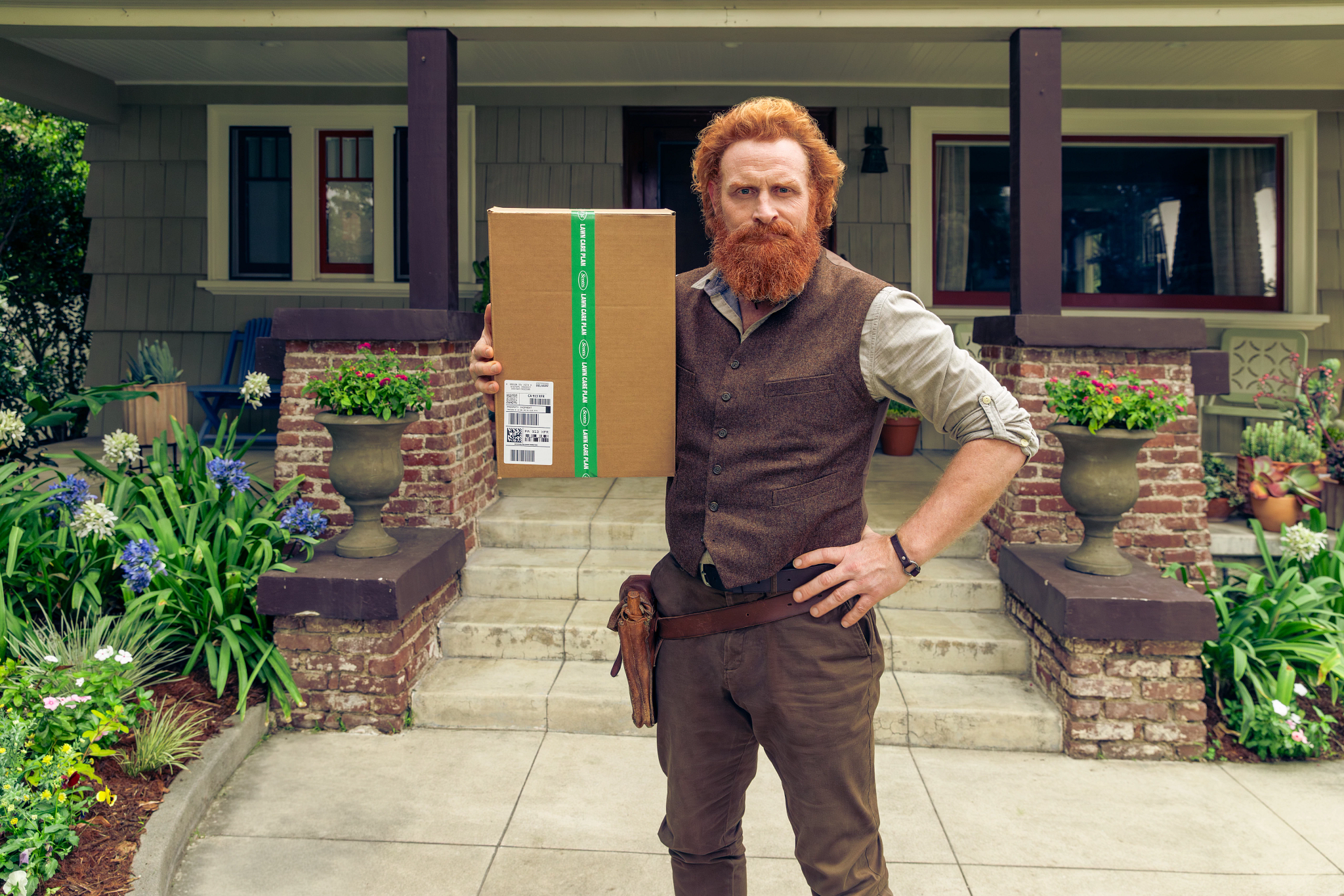 scotty with a phone standing in front of a porch holding a subscription box